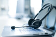 Call center operator desktop. Close-up of a headset on a laptop. Help desk. Workplace of a support service employee. Headphones with a microphone for voip on a computer keyboard.