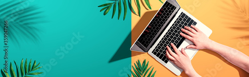 Fotografía Person using a laptop computer with tropical leaves from above