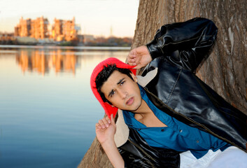 Handsome young hispanic man in a surprise pose in front of a river in Austin on a cold winter's day.