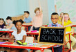 © Evgeniy Kalinovskiy - a small child an African-American schoolboy with glasses smiles and holds a sign that says 'Back to school' against the background of a group of children and a school class.