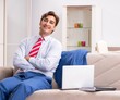 © Elnur - Young businessman working at home sitting on the sofa
