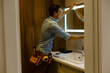 © Angelov - Man installing a mirror on wall in his renewed bathroom