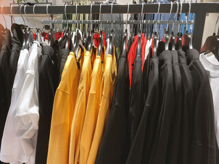 Collection outfit in hanging racks in clothing fashion store. Shirts and sweatshirts