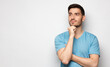 © Damir Khabirov - Banner of young man in blue t-shirt with dreamy cheerful expression, thinking, isolated on gray background with copy space for your ads