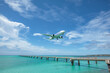 Landing airplane on emelardgreen ocean in summer