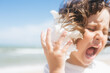 © sweetlaniko - Little girl wearing light t-short and light pink skirt at the sea beach with a big beautiful seashell. Summer vacation