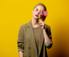 Wall Mural - Style blonde woman in jacket with Norwegian flag on yellow background