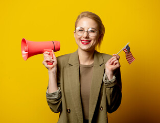 Wall Mural - Style blonde woman in jacket with flag of USA and megaphone on yellow background