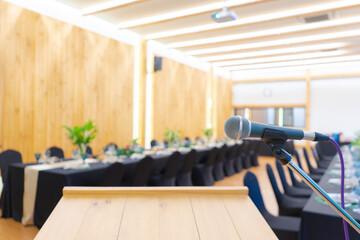 Close up to microphone beside the podium with blur long black table dinner time in tungsten warm light.