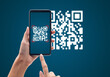 © Touchr - Hand using mobile smart phone scan Qr code on blue background. Cashless technology and digital money concept.