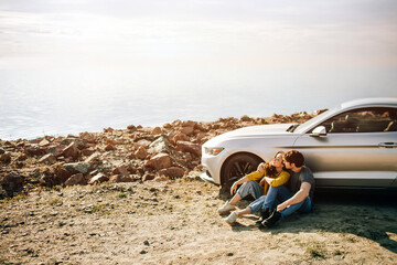 Wall Mural - Romantic couple is standing near a Muscle car on the beach. The handsome bearded man and an attractive young woman have a Love story.