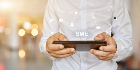 Businessman hand pressing button SME icon on virtual screen. Idea for Small and medium-sized enterprises business.