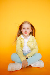 Beautiful portrat of young little girl in yellow studio and yellow bright clothes. Cute blonde child with plain healthy skin. Studio fashion model portrait