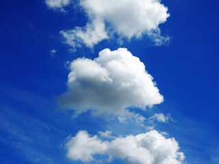 group of white flufly clouds on bright blue sky background