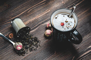 Wall Mural - Natural fragrant green herbal tea in a ceramic Cup on a wooden background with an empty space for text, a Cup of tea with a flower and a spoon with scattered tea leaves