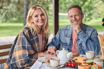 Wall Mural - Cheerful mature couple during breakfast in veranda outdoors