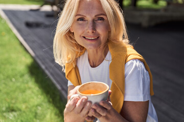 Wall Mural - Happy woman with cup of coffee on sunny day