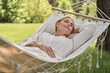 © Yakobchuk Olena - Happy mature female sleeping in hammock outdoors