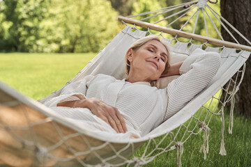 Wall Mural - Happy mature female sleeping in hammock outdoors