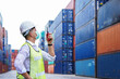 © mrk3PHOTO - new normal concept.inspector engineer or project engineer wear helmet and mask and use walkie talkie to contact the factory team or container yard.Remote execution to prevent Coronavirus infection