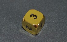 Gold Metallic D6 Six Sided Dice On Foam Surface In Bright Sunshine