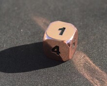 Copper Metallic D6 Six Sided Dice On Foam Surface In Bright Sunshine