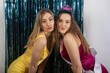 © Mat Hayward - Two smiling girls having fun together posing for a photo during a birthday party. Birthday girl is wearing a tiara and sash in front of a tinsel background for decoration