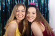 © Mat Hayward - Two smiling girls having fun together posing for a photo during a birthday party. Birthday girl is wearing a tiara and sash in front of a tinsel background for decoration