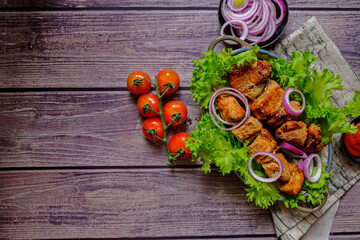 Skewers of Meat with sauce on wooden cutting board, ready to be served as summer party meal, view from above.