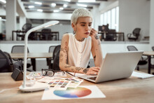 Creative occupation. Young stylish tattooed female designer working on new project while standing near office desk