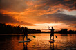 © fesenko - Beautiful rear view of two people on sup boards which floating on the river at sunset