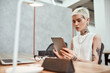 © Svitlana - Surfing the net. Portrait of young stylish blonde tattooed business woman using touchpad while sitting at her working place in the modern office. Digital technologies at work