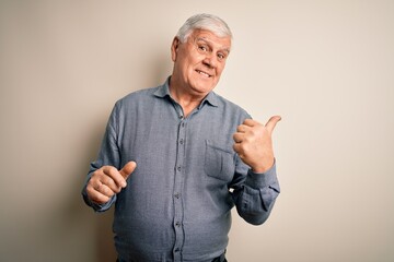 Wall Mural - Senior handsome hoary man wearing casual shirt standing over isolated white background smiling with happy face looking and pointing to the side with thumb up.