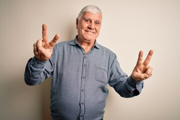 Wall Mural - Senior handsome hoary man wearing casual shirt standing over isolated white background smiling looking to the camera showing fingers doing victory sign. Number two.