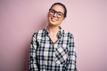 Wall Mural - Young beautiful brunette woman wearing casual shirt and glasses over pink background with a happy and cool smile on face. Lucky person.