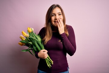 Sticker - Young blonde woman holding romantic bouquet of yellow tulips flowers over pink background laughing and embarrassed giggle covering mouth with hands, gossip and scandal concept