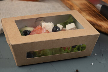 Eco packaging - Greek salad in a craft box for delivery. Vegan food.