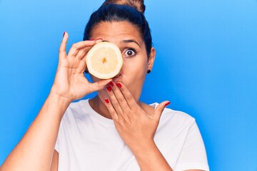 Sticker - Young beautiful brunette woman holding slice of lemon covering mouth with hand, shocked and afraid for mistake. surprised expression