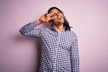 Wall Mural - Young handsome african american afro man with dreadlocks wearing casual shirt Doing peace symbol with fingers over face, smiling cheerful showing victory