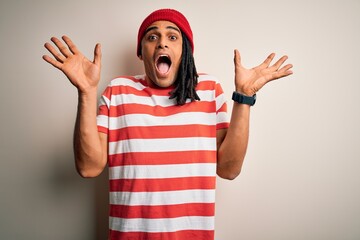 Wall Mural - Young handsome african american man with dreadlocks wearing striped t-shirt and wool hat celebrating crazy and amazed for success with arms raised and open eyes screaming excited. Winner concept