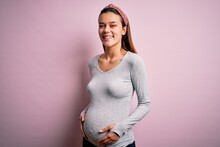 Young Beautiful Teenager Girl Pregnant Expecting Baby Over Isolated Pink Background With A Happy And Cool Smile On Face. Lucky Person.
