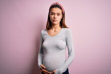 Young Beautiful Teenager Girl Pregnant Expecting Baby Over Isolated Pink Background Skeptic And Nervous, Frowning Upset Because Of Problem. Negative Person.