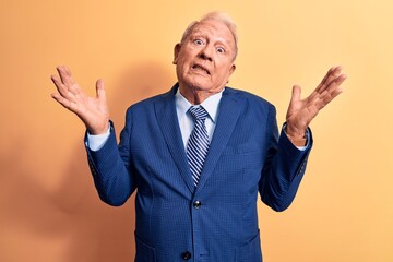 Sticker - Senior handsome grey-haired businessman wearing elegant suit over yellow background clueless and confused with open arms, no idea and doubtful face.