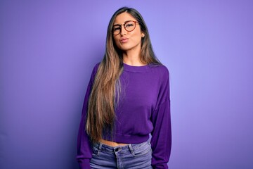 Wall Mural - Young beautiful smart woman wearing glasses over purple isolated background looking at the camera blowing a kiss on air being lovely and sexy. Love expression.