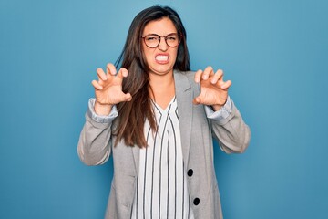 Sticker - Young hispanic business woman wearing glasses standing over blue isolated background smiling funny doing claw gesture as cat, aggressive and sexy expression