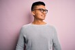 © Krakenimages.com - Young handsome latin man wearing casual sweater and glasses over pink background looking away to side with smile on face, natural expression. Laughing confident.