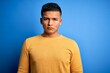 © Krakenimages.com - Young handsome latin man wearing yellow casual sweater over isolated blue background Relaxed with serious expression on face. Simple and natural looking at the camera.
