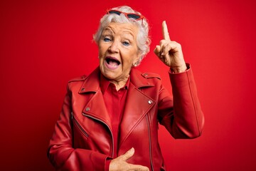 Wall Mural - Senior beautiful grey-haired woman wearing casual red jacket and sunglasses pointing finger up with successful idea. Exited and happy. Number one.