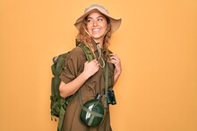 Young Blonde Explorer Woman With Blue Eyes Hiking Wearing Backpack And Water Canteen Looking Away To Side With Smile On Face, Natural Expression. Laughing Confident.
