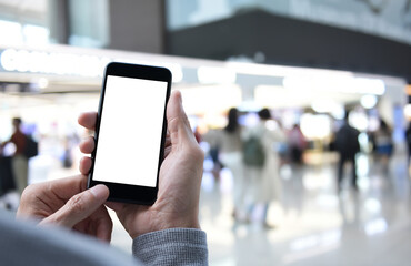Mockup of man using blank screen mobile phone with people shopping in department store for mobile banking online payment concept